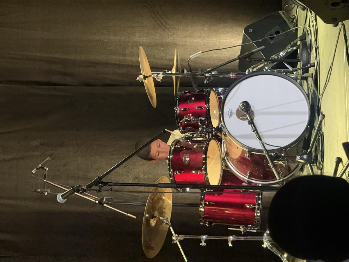 Un élève de batterie sur scène pendant le spectacle de musique